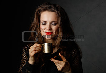 Woman with red lips enjoying cup of coffee on dark background