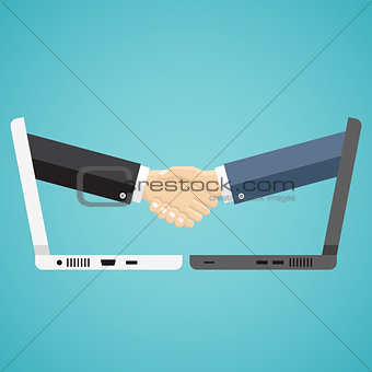 Businessmen shake hands from two computers.