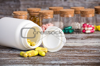 Yellow pills in front of plastic container
