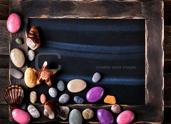 Blackboard decorated with sea objects shaped candies and pebbles