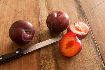 Whole and cut plums with knife on table