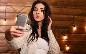 Portrait of a beautiful brunette taking a selfie with her smart phone at home
