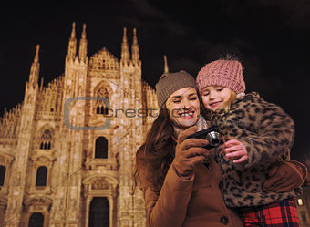 Mother and daughter looking on photos in camera near Duomo