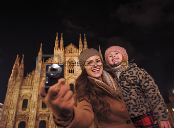 Happy mother and daughter sightseeing and taking photos in Milan