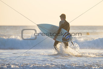 Silhouette of surfer on beach with surfboard.