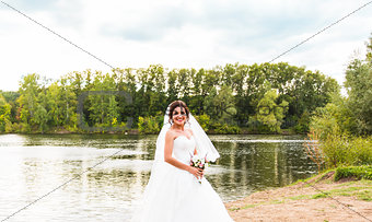 bride in a white dress with  wedding bouquet at the lake