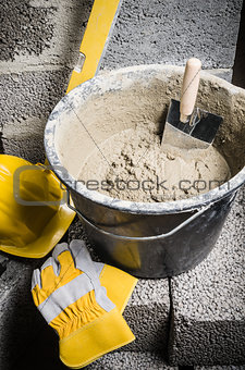 Tools for bricklayer bucket with a solution and a trowel, close-