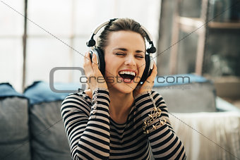 Happy young woman listening music in loft apartment