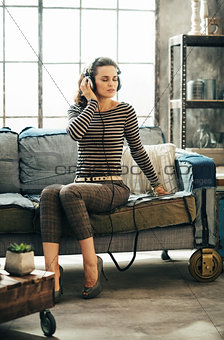 Woman listening to music through headphones in loft apartment