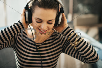 Woman listening to music in loft apartment. Close up portrait.