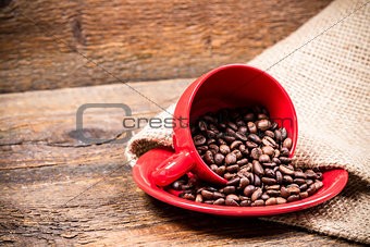 Red coffeecup and plate with spilled coffeebeans