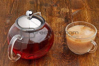 Set glass teapot and cup of tea with milk