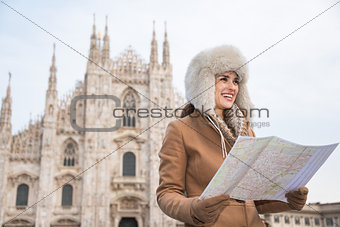 Smiling woman traveler with map looking aside near Duomo, Milan