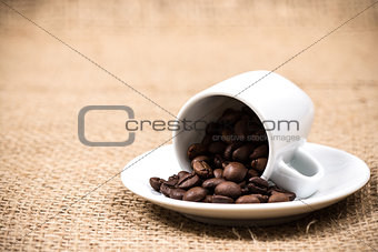Coffeecup with coffeebeans on gunny textile