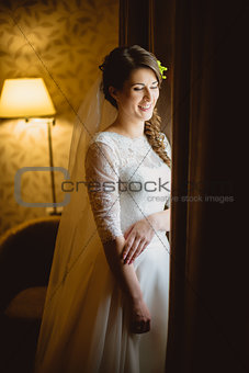 bride in a white dress standing near window