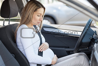 Pregnant woman behind the steering wheel having contractions