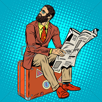 Bearded hipster traveler reading a newspaper