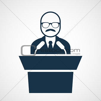Bald-headed man at rostrum - speaker in glasses at tribune