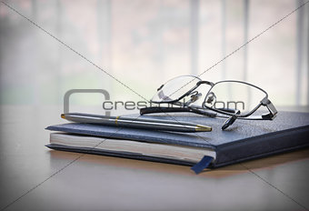 Glasses and pen on a book