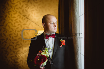 The bride standing near a window with bouquet
