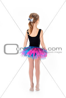 Little ballerina in purple skirt standing on white background