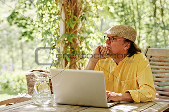 Pensive senior man with laptop