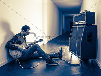 Playing his electric guitar in the hallway