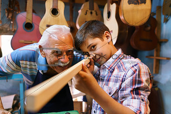 Old Man Luter Teaching Grandson Boy Chiseling Wood