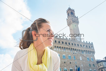 Smiling woman standing near Palazzo Vecchio and looking aside