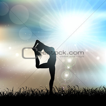 Silhouette of a female in a yoga pose in sunny landscape