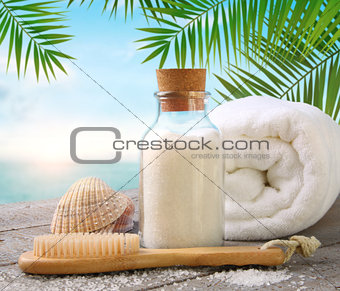 Fluffy towels with sea salt and seashells on beach table