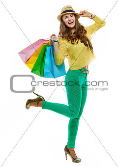 Cheerful woman in hat and bright clothes with shopping bags