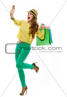 Woman in hat and bright clothes with shopping bags taking selfie
