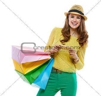 Woman in hat with shopping bags writing sms on smartphone