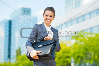Smiling business woman in office district holding briefcase