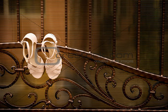 White wedding shoes hang a wrought iron fence
