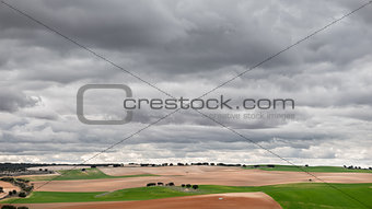 Green cultivated fields against cloudy stormy sky