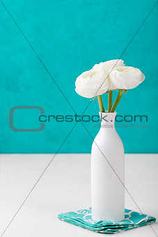 White ranunculus flowers in a ceramic vase