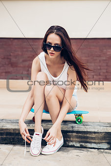 Hipster girl with skateboard on the street.