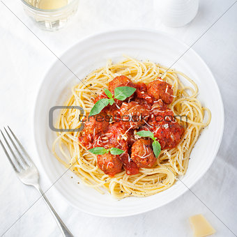 Meatballs in tomato sauce and fresh basil with spaghetti on a white plate Top view