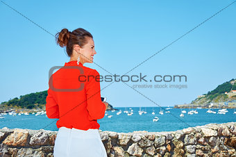 Seen from behind woman with mobile standing in front of lagoon