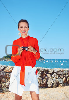 Happy woman with photo camera standing in front of lagoon