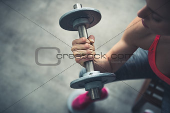 Closeup on fitness woman workout with dumbbell in urban loft gym