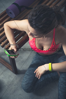 Fitness woman writing sms while sitting in urban loft gym