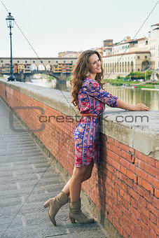 Happy young woman in a dress on embankment near Ponte Vecchio