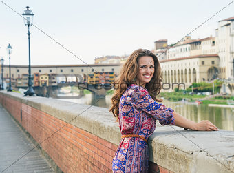 Smiling young woman in a dress on embankment near Ponte Vecchio