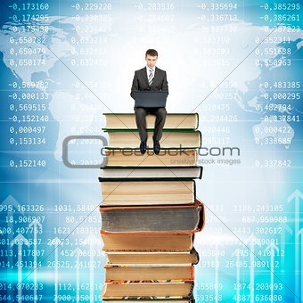 Businessman with laptop sitting on stack of books