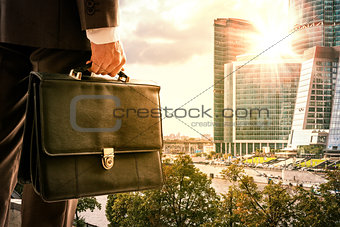 Businessman with suitcase against modern city