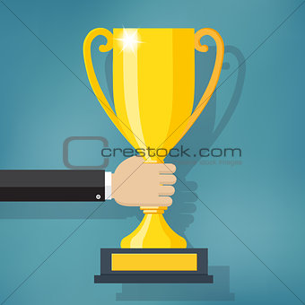 Hand holding a winner trophy cup.