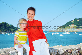 Happy mother and child in front of lagoon with yachts